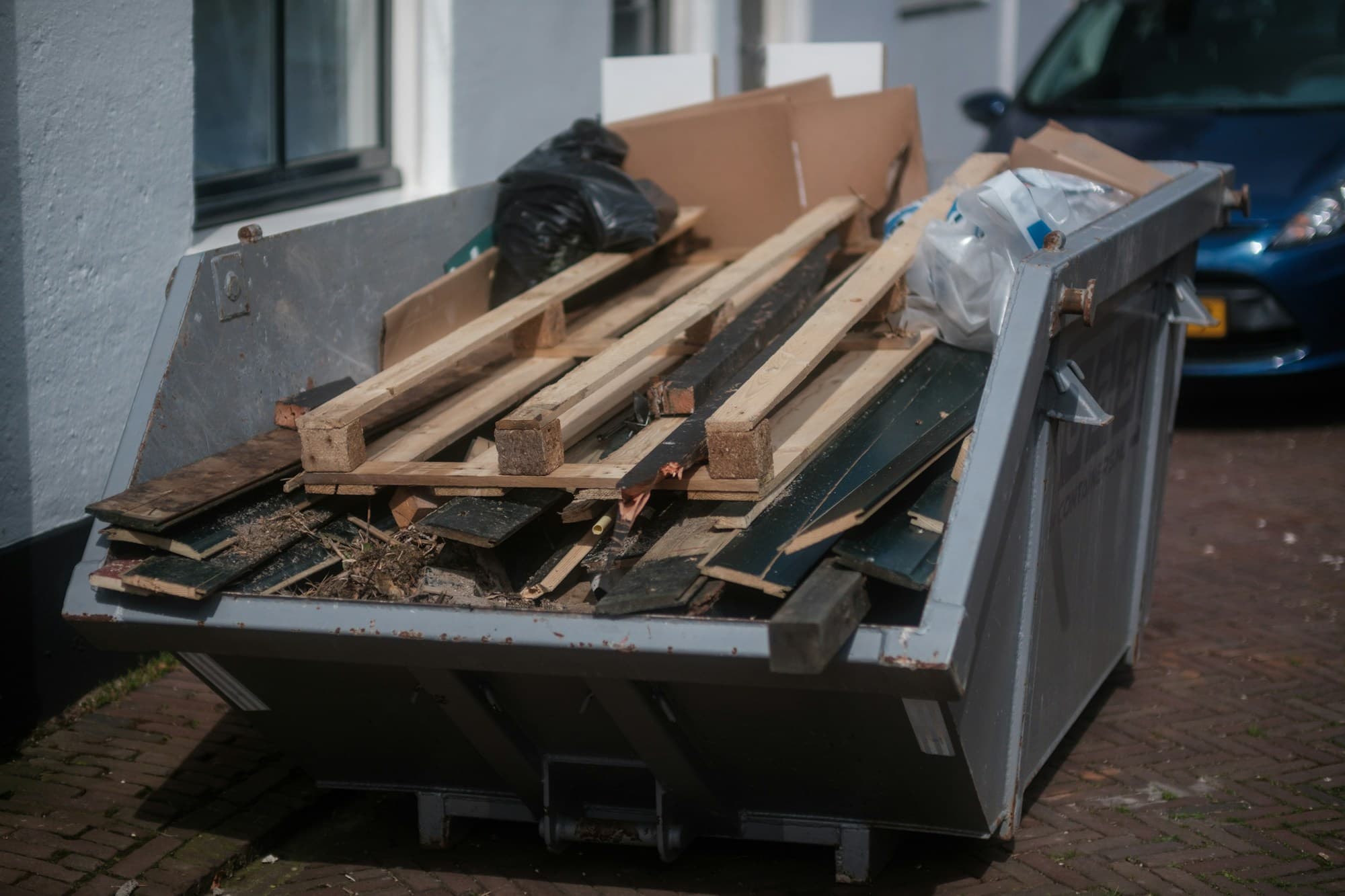Open debris container loaded with lumber offcuts, boards and renovation waste